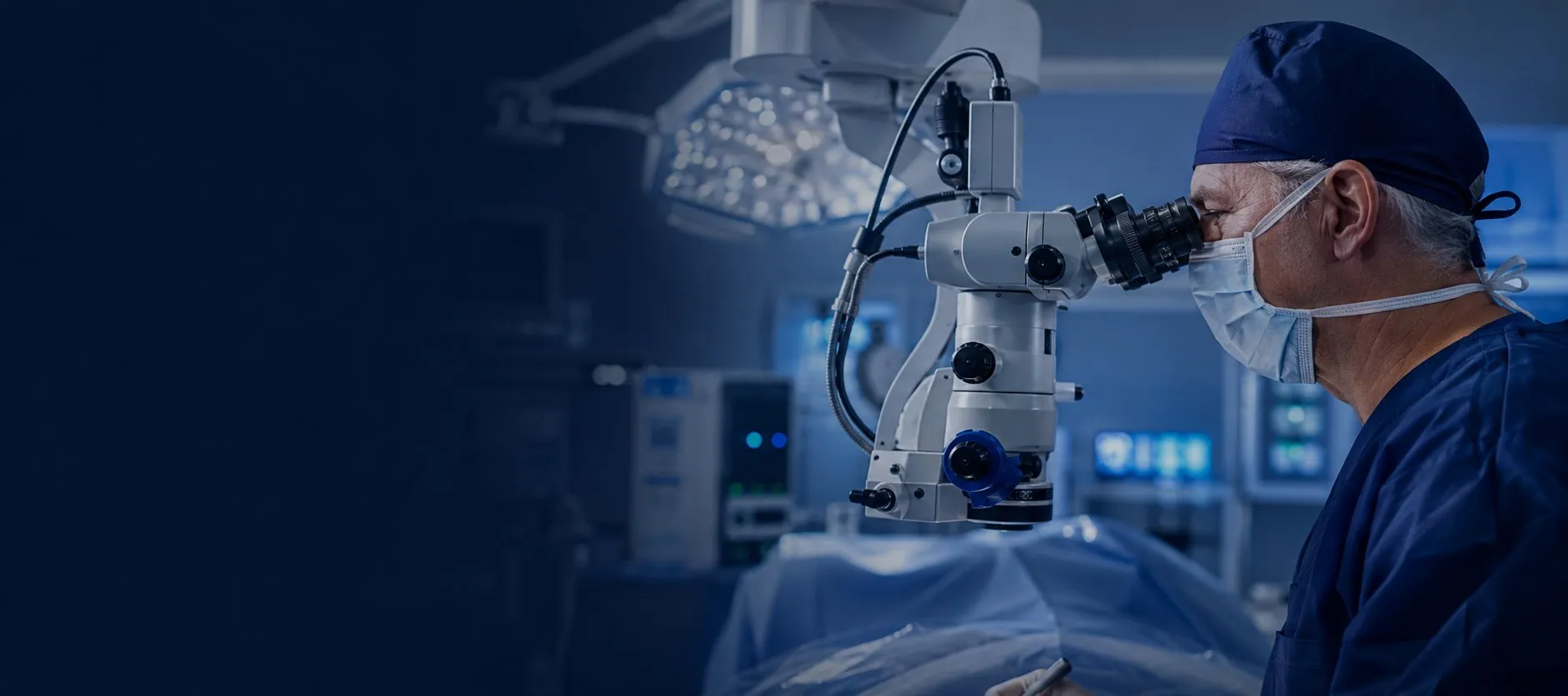 Ear surgeon at an operating microscope in a blue-lit theatre